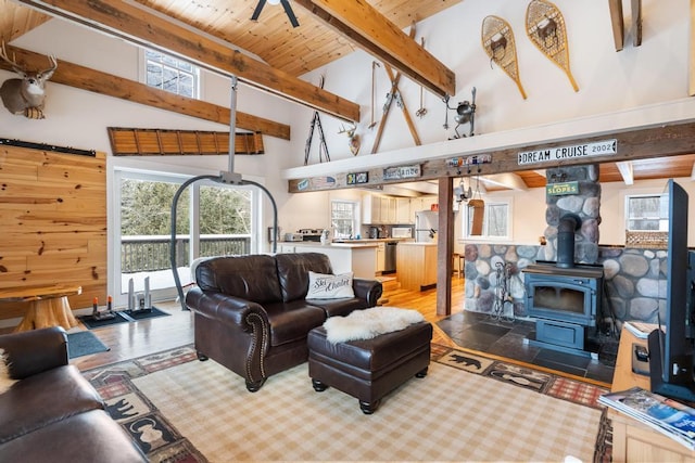 living area with high vaulted ceiling, wood finished floors, wood ceiling, beam ceiling, and a wood stove