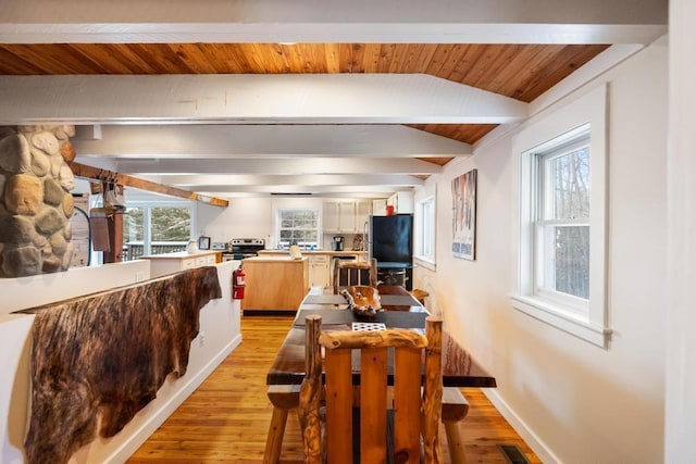 dining room featuring baseboards, light wood-style flooring, visible vents, and beam ceiling