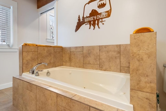 bathroom featuring baseboards, plenty of natural light, a garden tub, and tile patterned floors