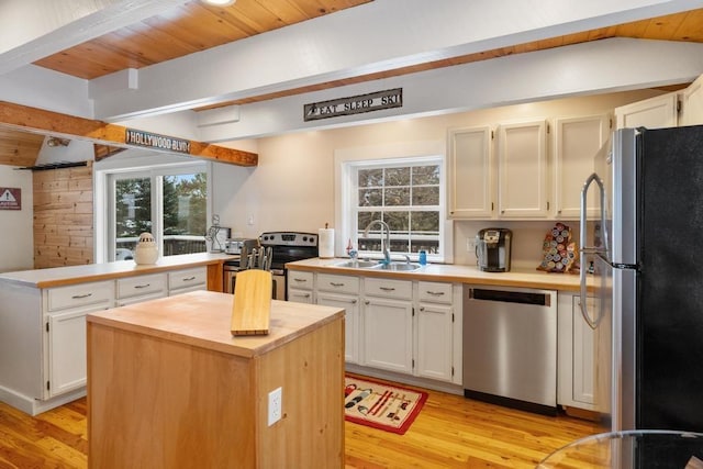 kitchen with stainless steel appliances, a center island, white cabinets, and a sink