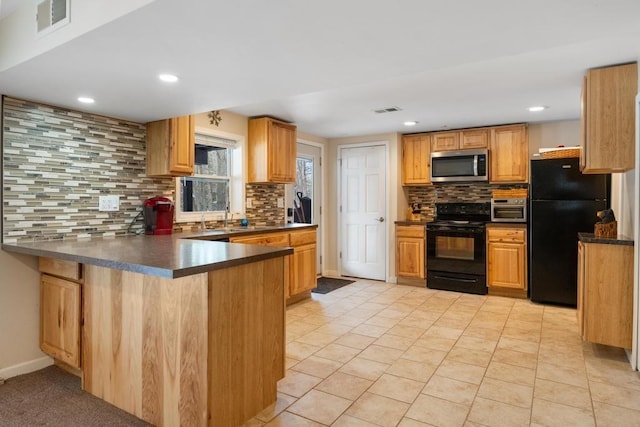 kitchen with a peninsula, visible vents, black appliances, tasteful backsplash, and dark countertops