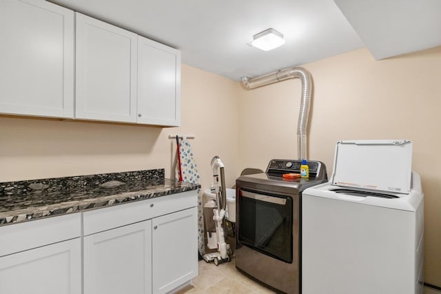 clothes washing area with washer and dryer, cabinet space, and light tile patterned flooring