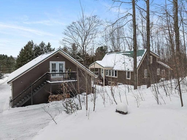 snow covered back of property featuring stairway