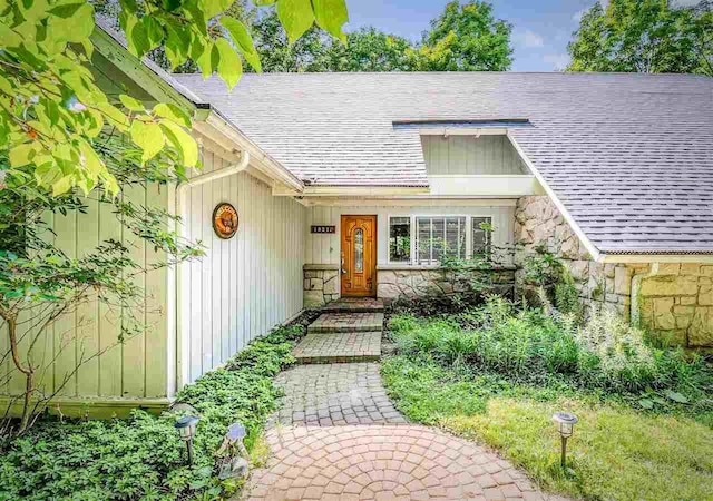 property entrance featuring stone siding and roof with shingles