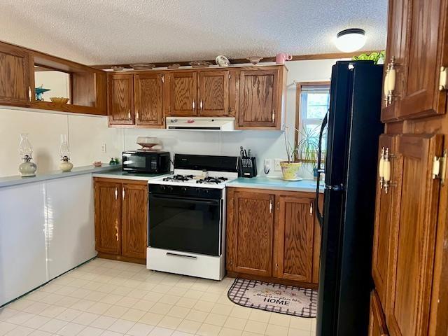 kitchen featuring brown cabinets, ventilation hood, a textured ceiling, light countertops, and black appliances