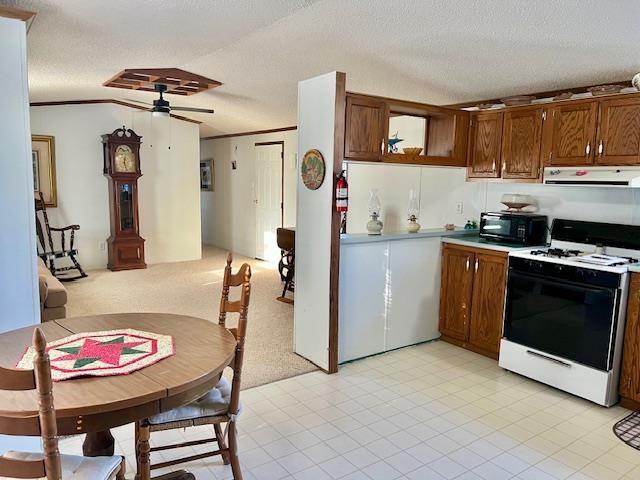 kitchen with a ceiling fan, a textured ceiling, white gas range oven, black microwave, and exhaust hood