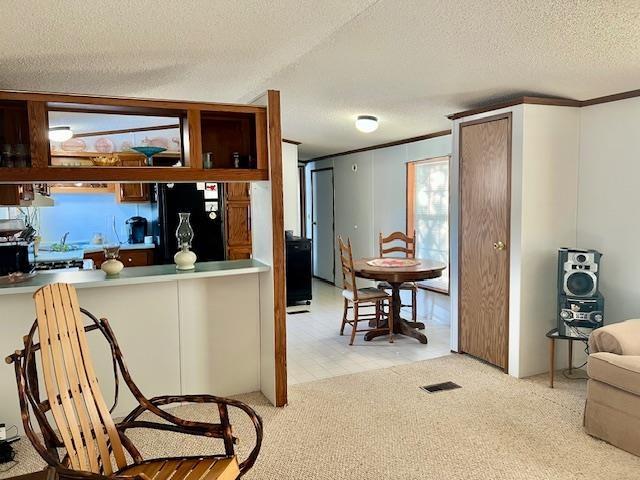 kitchen with light carpet, visible vents, a textured ceiling, and freestanding refrigerator