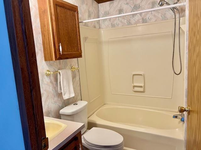 full bath featuring toilet, wallpapered walls, tub / shower combination, and vanity