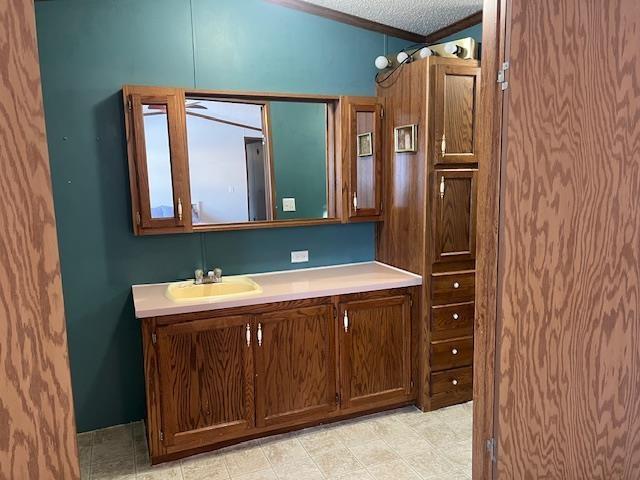 bathroom with a textured ceiling, ornamental molding, and vanity