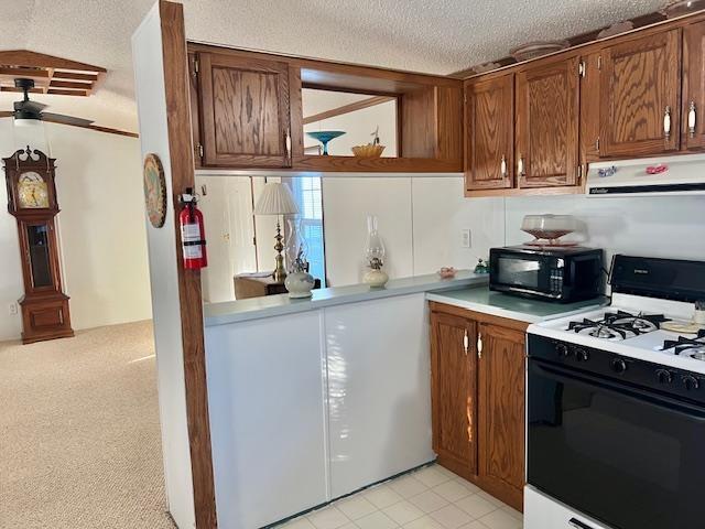 kitchen with brown cabinetry, range with gas cooktop, a textured ceiling, under cabinet range hood, and black microwave