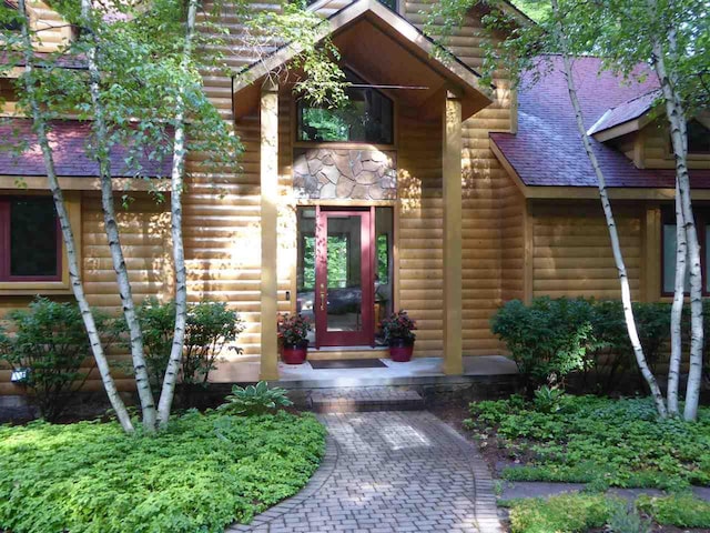 doorway to property with log veneer siding and roof with shingles