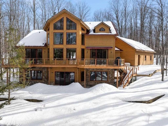 view of front of home with a deck, stone siding, and stairway