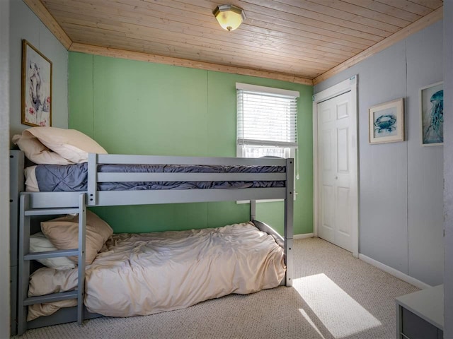 carpeted bedroom featuring a closet, wooden ceiling, and baseboards