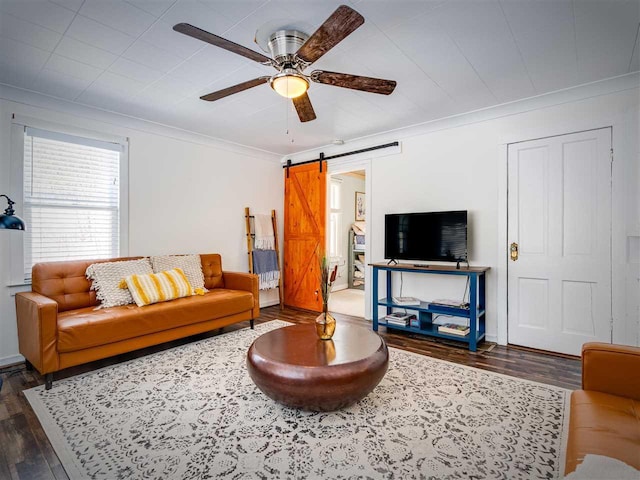 living area with a ceiling fan, wood finished floors, crown molding, and a barn door