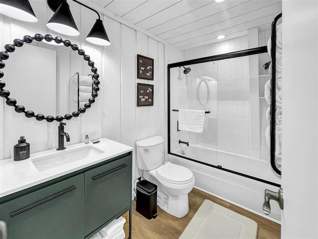 full bath with bath / shower combo with glass door, vanity, wood finished floors, and toilet