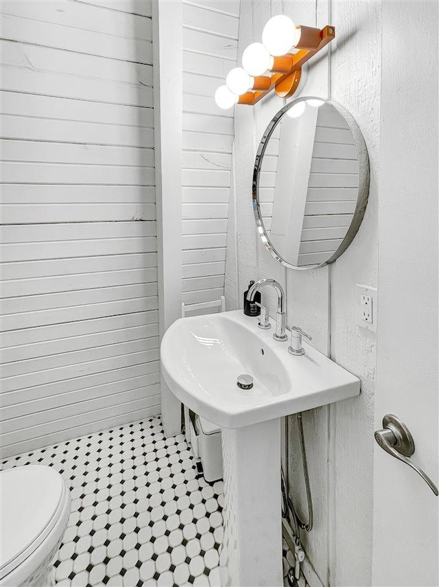 half bath with wooden walls and toilet