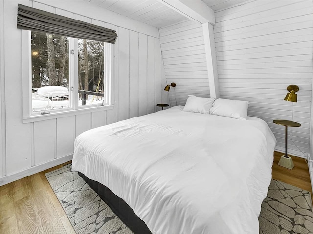 bedroom with beamed ceiling and wood finished floors