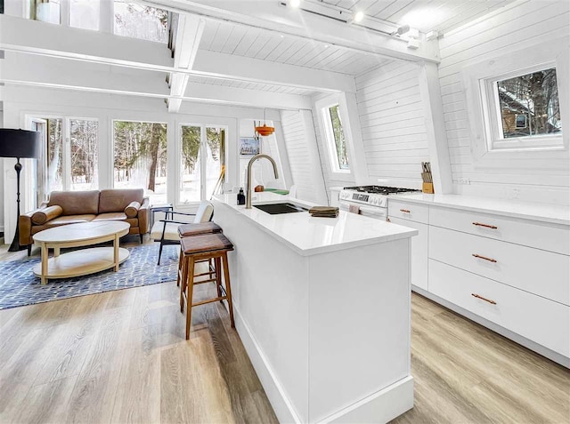 kitchen with a breakfast bar, white cabinets, a sink, and light wood-style flooring