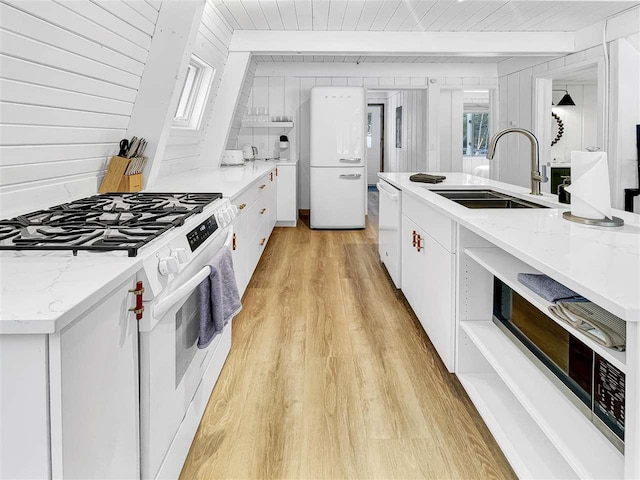 kitchen featuring light wood-type flooring, white appliances, white cabinetry, and a sink