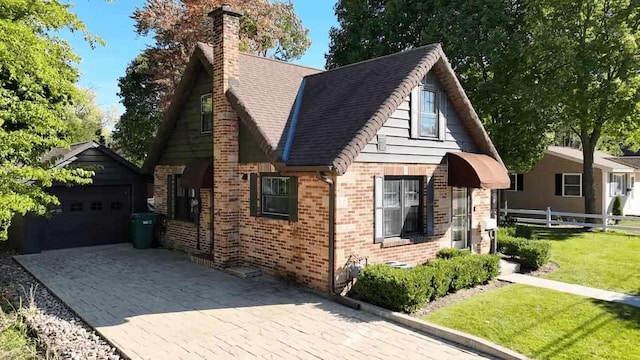 view of front of house featuring brick siding, fence, roof with shingles, a chimney, and a front yard