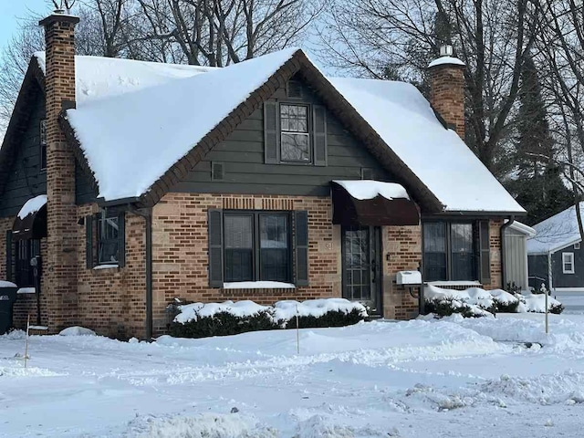 view of front of property featuring brick siding and a chimney