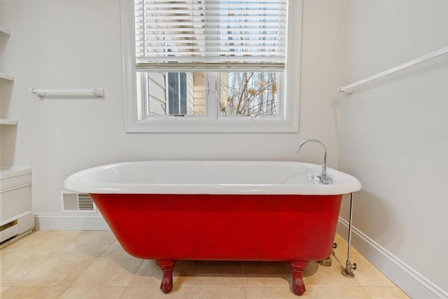 bathroom featuring tile patterned flooring, a freestanding tub, and visible vents