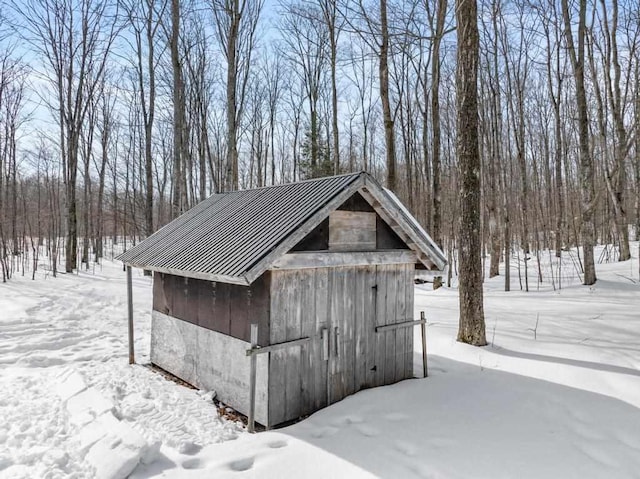 snow covered structure featuring a storage unit and an outdoor structure