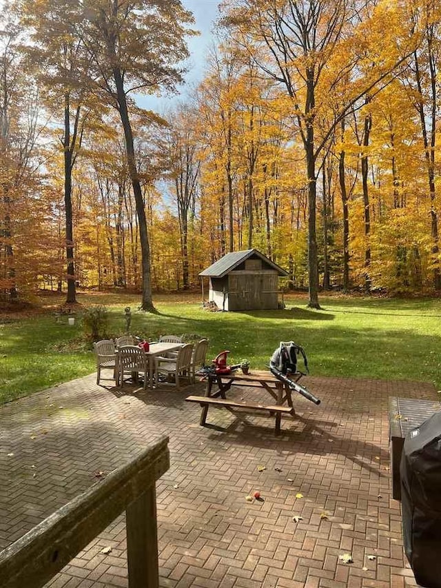 view of home's community featuring a patio area, outdoor dining area, a lawn, and an outdoor structure