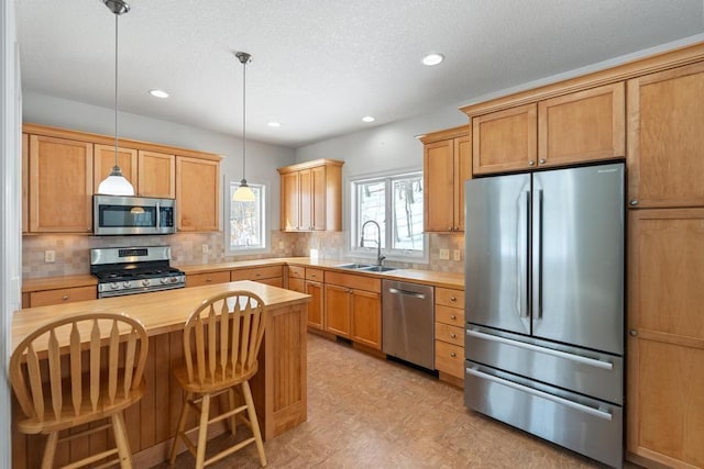 kitchen featuring pendant lighting, backsplash, appliances with stainless steel finishes, a sink, and butcher block countertops