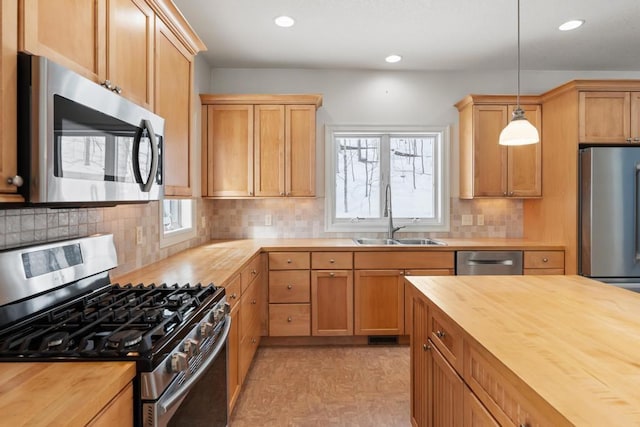 kitchen featuring recessed lighting, butcher block countertops, a sink, appliances with stainless steel finishes, and decorative light fixtures