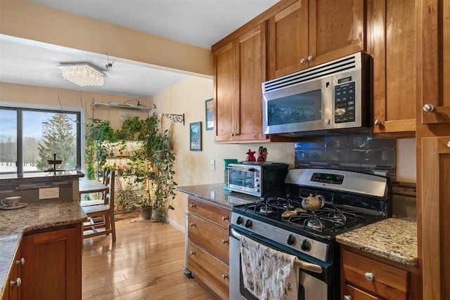 kitchen with brown cabinets, stone counters, a toaster, and stainless steel appliances