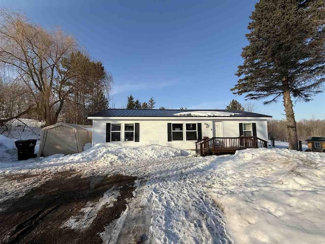 manufactured / mobile home featuring a deck, metal roof, a detached garage, and an outbuilding