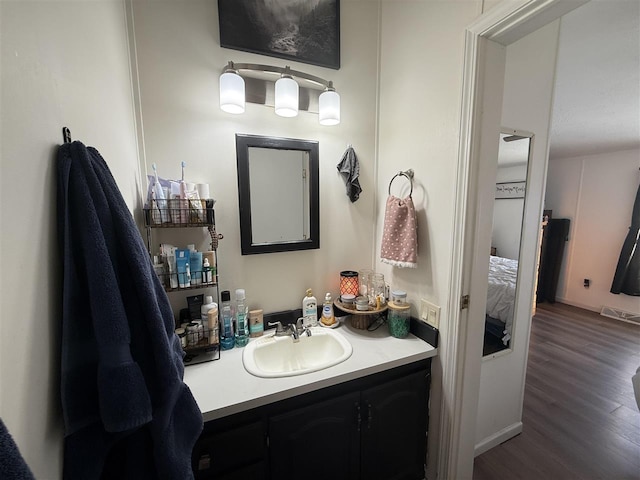 ensuite bathroom featuring wood finished floors, vanity, and connected bathroom