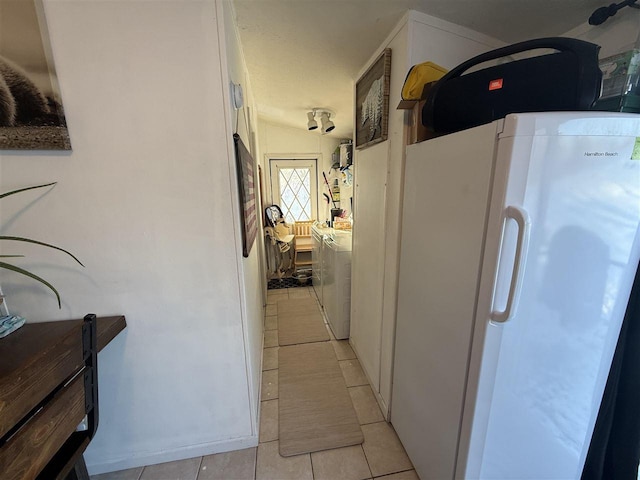 hallway featuring washer and dryer and light tile patterned flooring