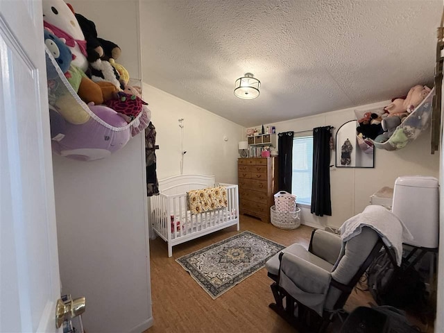 bedroom with a textured ceiling and wood finished floors