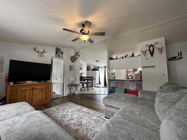 living area featuring a textured ceiling, vaulted ceiling, wood finished floors, and a ceiling fan