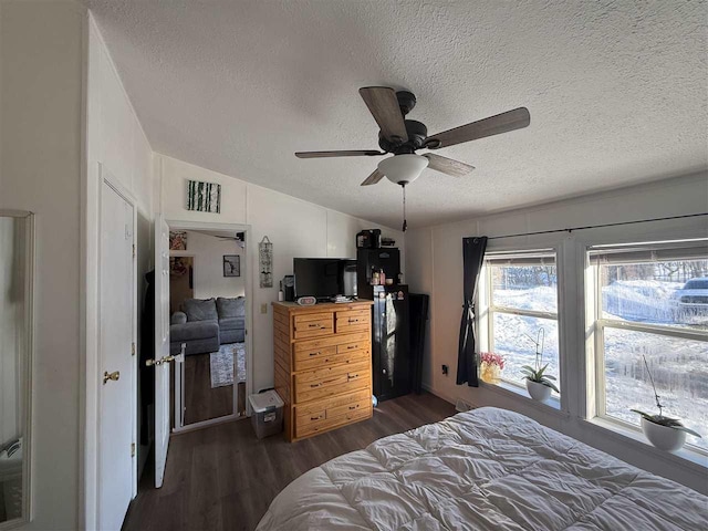 bedroom featuring dark wood finished floors, visible vents, vaulted ceiling, a textured ceiling, and ceiling fan