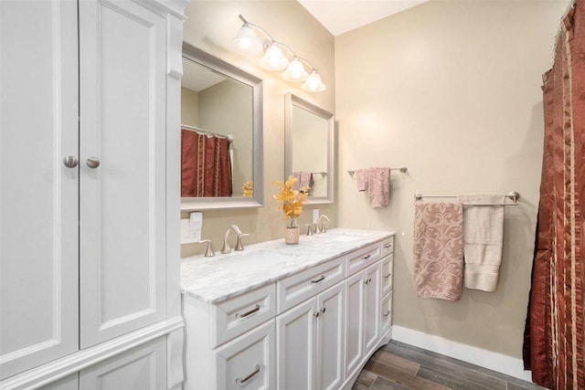 bathroom featuring double vanity, a sink, baseboards, and wood finished floors