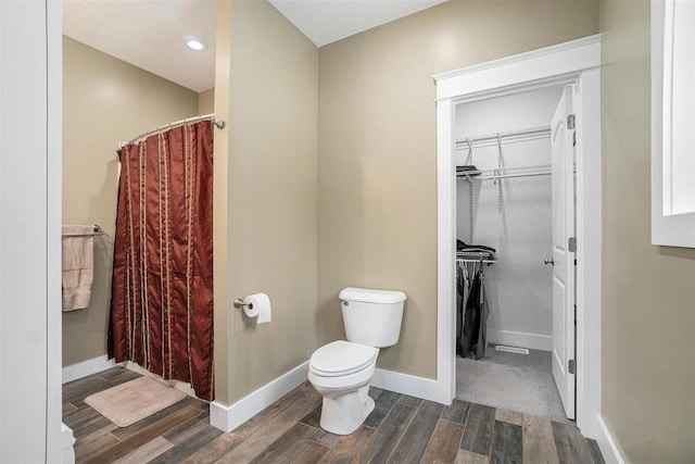 bathroom with a shower with shower curtain, baseboards, toilet, and wood finished floors