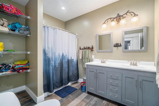 bathroom with wood finished floors, a sink, toilet, and baseboards