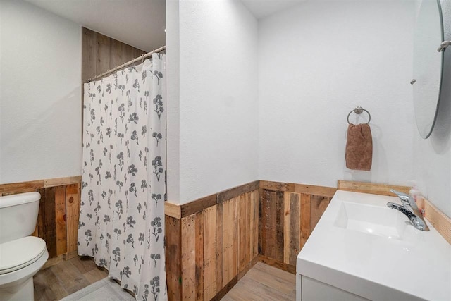 full bath with toilet, wooden walls, wood finished floors, and a shower with shower curtain