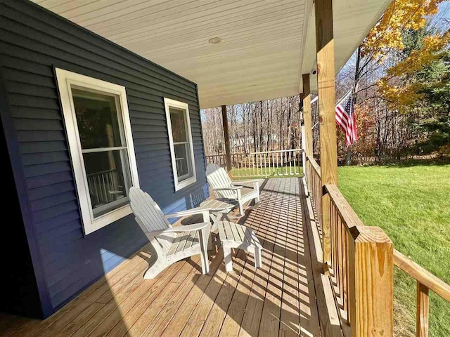 wooden deck featuring covered porch and a lawn