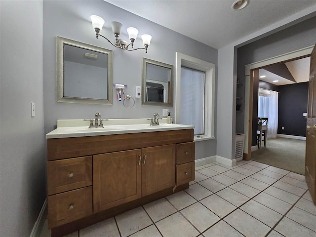 bathroom with baseboards, tile patterned flooring, a sink, and double vanity