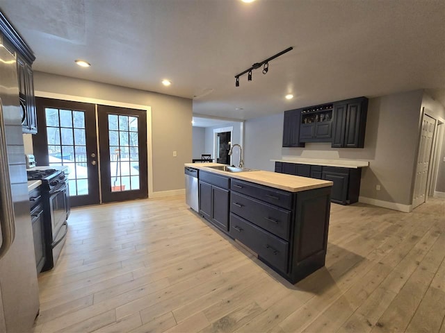 kitchen featuring a sink, french doors, stainless steel dishwasher, light wood-type flooring, and gas range oven