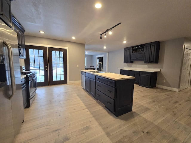 kitchen featuring baseboards, appliances with stainless steel finishes, french doors, and a sink