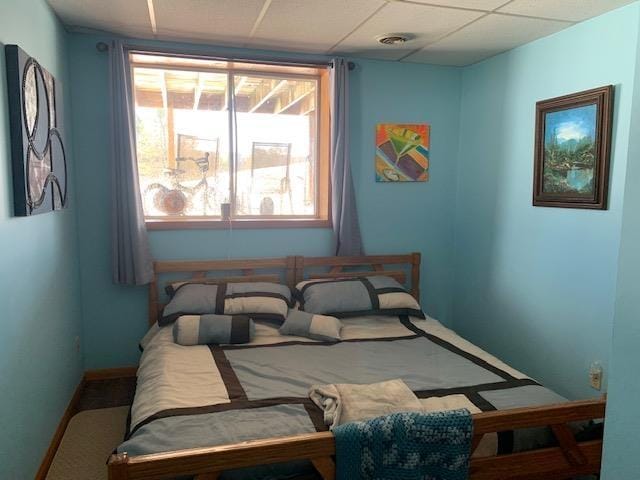 bedroom featuring a paneled ceiling and baseboards