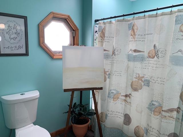 full bath with a shower with shower curtain and toilet