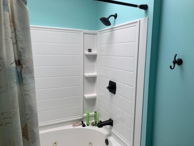 bathroom with a combined bath / shower with jetted tub