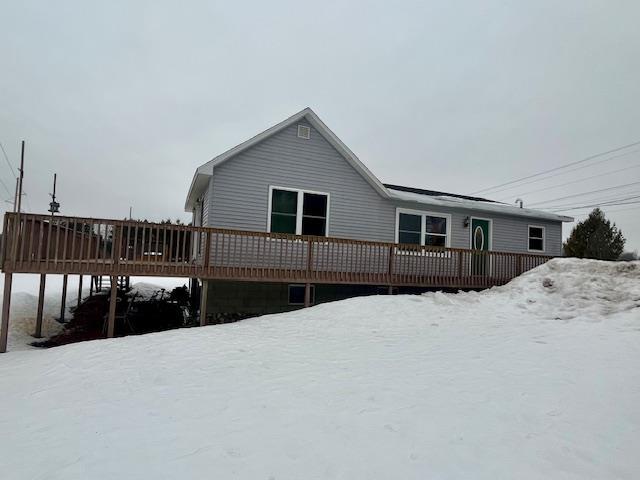 snow covered rear of property with a deck