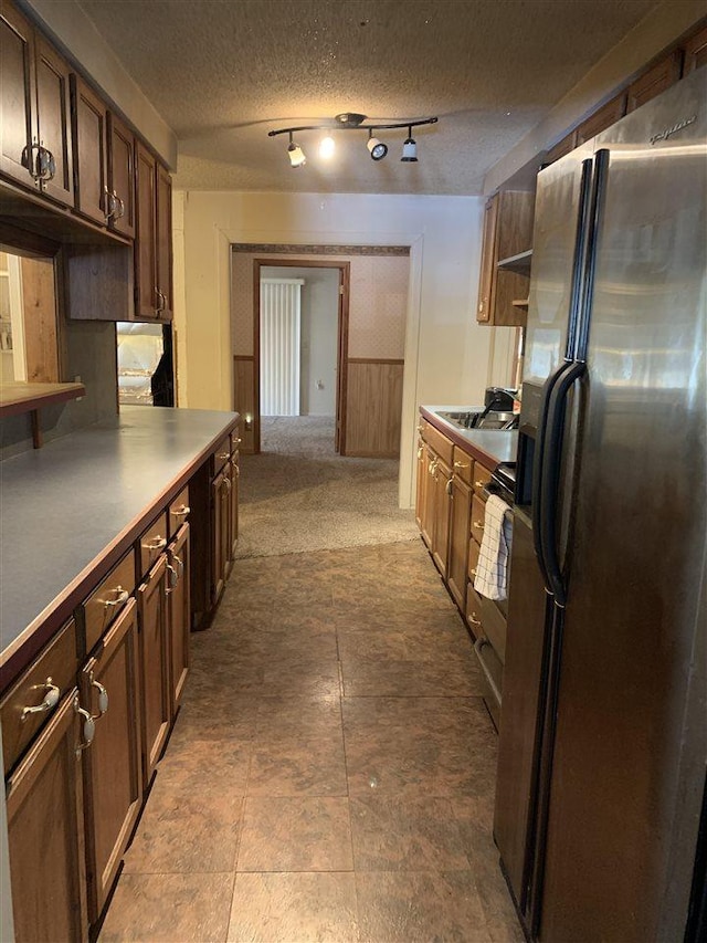 kitchen with dark brown cabinetry, refrigerator with ice dispenser, and a textured ceiling